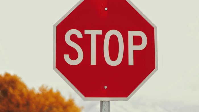 Stop-Schild mit Blättern und Bild im Hintergrund